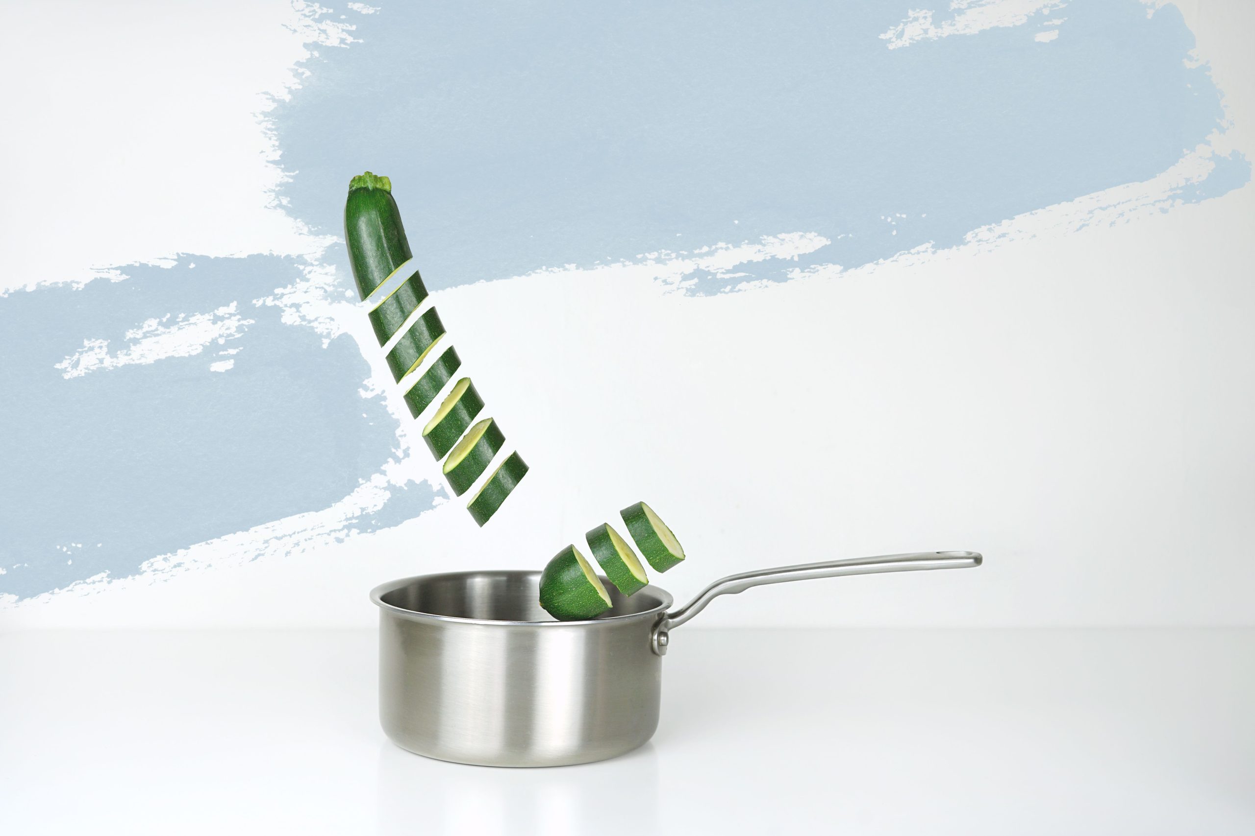 Courgettes émincées flottant au-dessus d'une poêle
