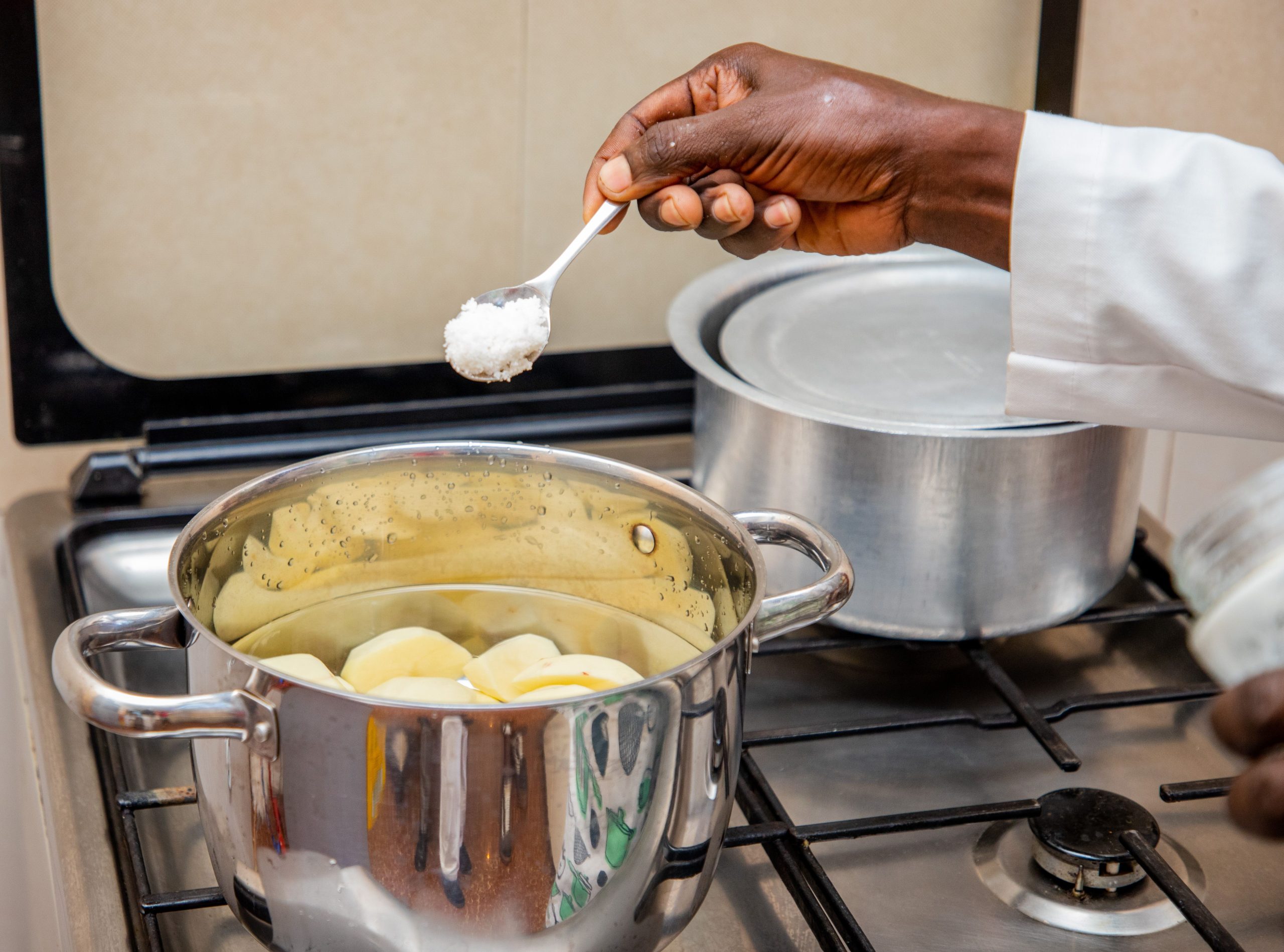 Cuisinier ajoutant du sel à des pommes de terre en ébullition