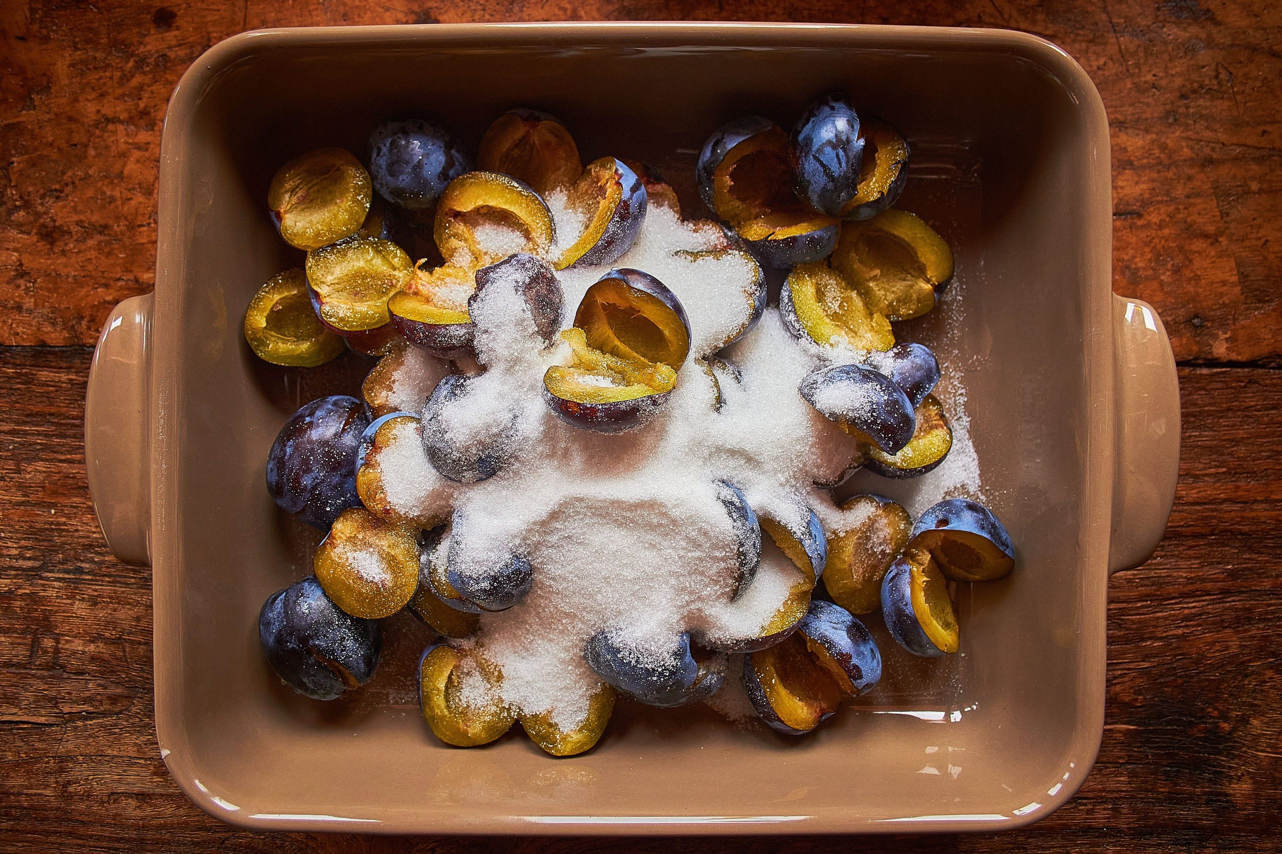 Mirabelles tranchées saupoudrées de sucre sur plateau cuisson